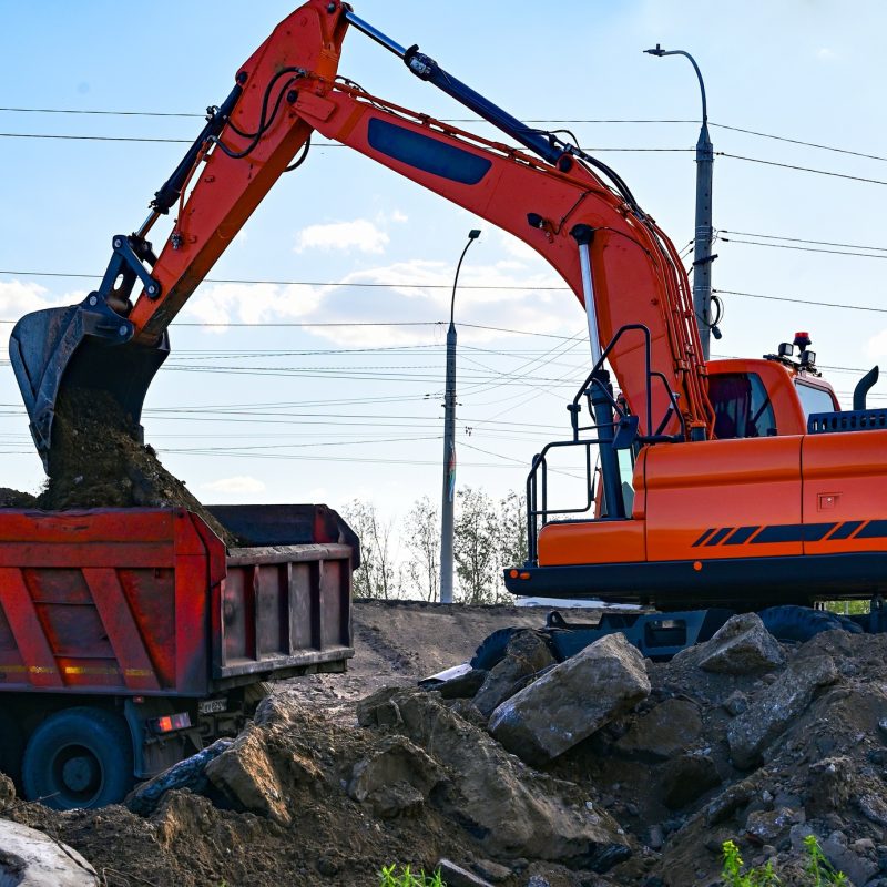 Excavator during earthmoving at open pit on blue sky background. Construction machinery